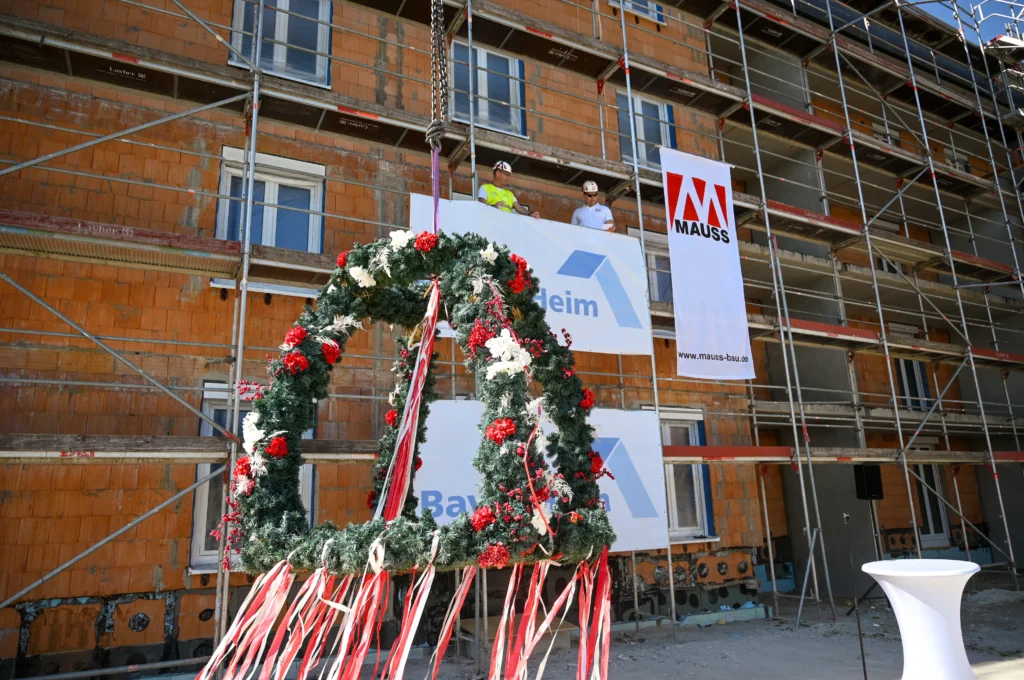 Richtfest Dinkelsbühl, Richtkrone im Vordergrund, zwei Mitarbeiter auf Gerüst im Hintergrund