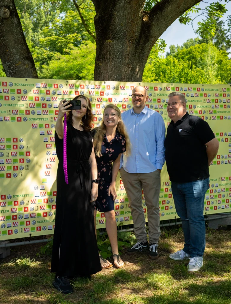 Sponsoren der Kulturinsel Wöhrmühle 2025, Gruppenfoto vor der Sponsorenwand, eine Person schießt ein Selfie von der Gruppe