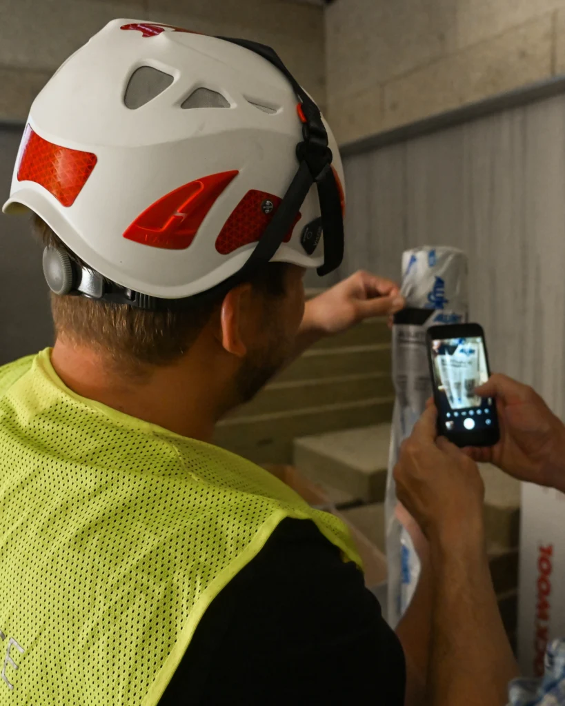 Zwei Mitarbeiter von MAUSS BAU führen auf einer Baustelle, mit Hilfe eines Smartphones, Überprüfungen durch