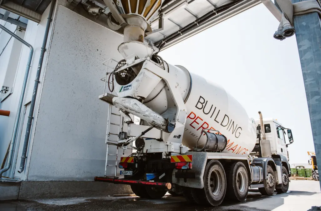 Fahrbarer Betonmischer wird im Betonmischwerk über den Trichter befüllt
