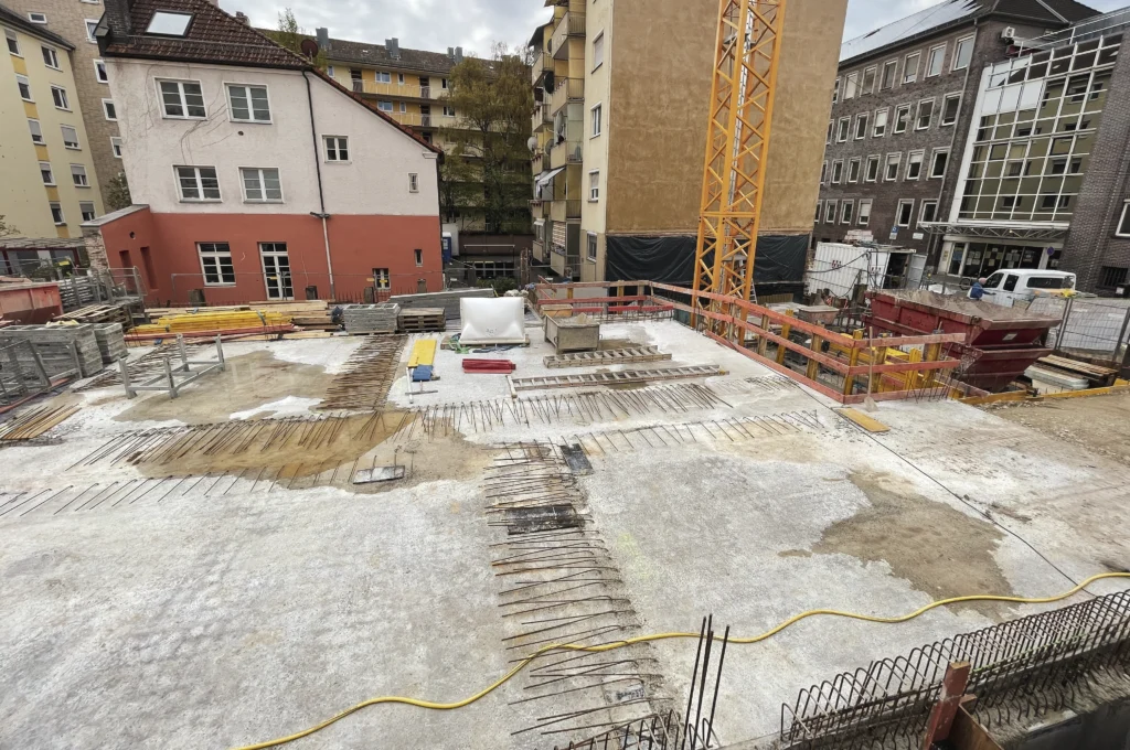 Das Bild zeigt die Decke des Untergeschosses aus Beton mit klaren Flächen und mehreren senkrecht herausragenden Stahlstäben. Die Betonfläche ist eben ausgeführt und vorbereitet für die weiteren Rohbauarbeiten.