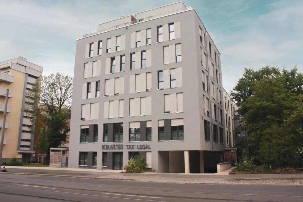 Mehrstöckiges Bürogebäude mit geschlossenen Fensterläden und der Aufschrift 'KRAUSS TAX LEGAL' an der Fassade.